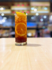 Glass of tasty iced tea with lemon in a glass on wood table