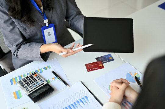 A female banker showing something on tablet screen while discussing with her client