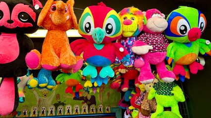Bright big toys hang in a row in an amusement park Raccoon dog parrot and other very bright colors Gifts for players playland prizes 