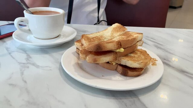 Toasted bread with butter and kaya, and milk tea on table. Asian breakfast. 