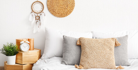 Cozy bedroom with stylish dream catcher hanging on white wall