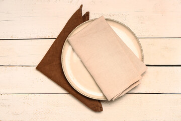 Plate with napkins on light wooden background