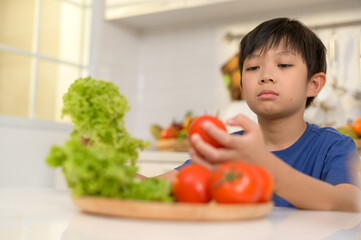  Asian boy feeling bored , unhappy to eat vegetables , health care concept