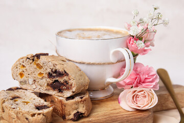 Board with cup of coffee, delicious biscotti cookies and beautiful flowers on white table