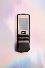 Old mobile phone on holographic background. retro, vintage and nostalgia style. Y2K design trend