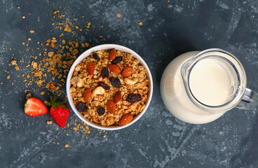 Obraz na płótnie Canvas Bowl with tasty granola and jug of milk on blue background