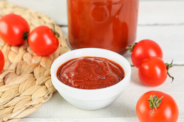 Bowl of tasty tomato paste on white wooden background