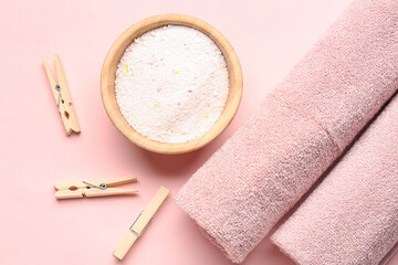 Laundry detergent, clothespins and rolled towels on pink background