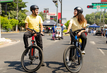 Friends man and woman cyclists using helmets  riding a bike in the road in a sunny day