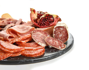 Slate plate with assortment of tasty deli meats isolated on white background, closeup