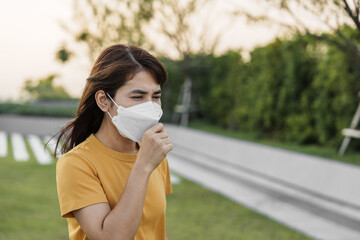 young Asian woman wearing N95 respiratory mask protect and filter pm2.5 or particulate matter against bad Air Pollution in City. Air Quality Index, AQI, Unhealthy, healthcare concept