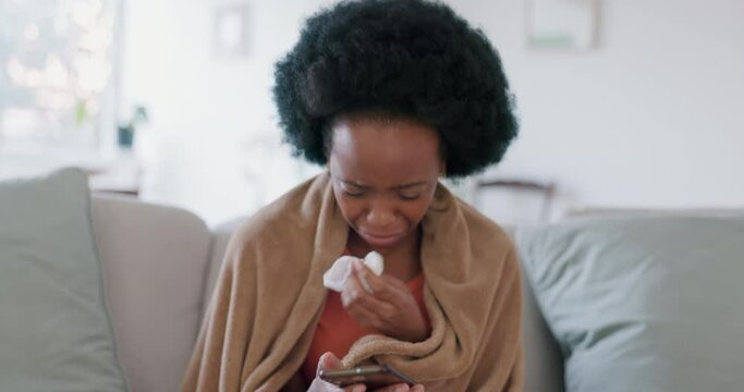 Sick, sneeze and phone with black woman using tissue on sofa and texting on her phone for medical, healthcare or illness. Virus, allergy or cold with young female with blanket in living room at home