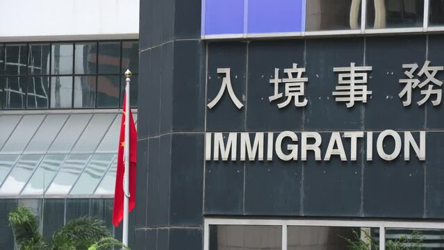 People's Republic of China flag blowing in the wind next to the immigration department tower.