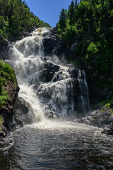 Ouiatchouan Waterfall in the forest of Quebec, Canada, among trees