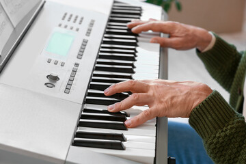 Fototapeta na wymiar Mature man playing synthesizer at home, closeup
