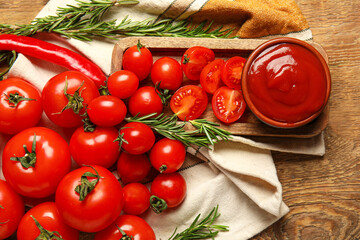 Bowl with tasty ketchup and fresh vegetables on wooden background