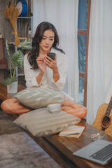 Young Asian woman student or freelancer enjoy playing social media, chatting, online shopping watching internet platform or play game by smart phone or mobile phone. Weekend activity, relaxing or rest