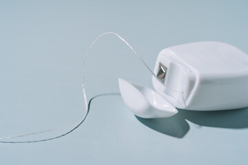 Dental floss in a white box close-up on a blue background.