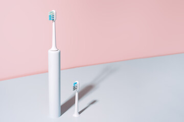 Electric toothbrush with brush head against blue-pink background.