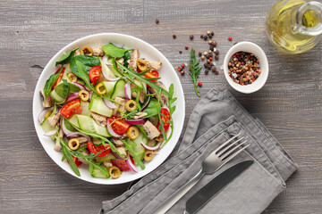 Fresh salad with vegetables and fish. Arugula, spinach, cucumbers, tomato, onions and fish in a plate on the table. Diet nutrition. Top view. Copy space