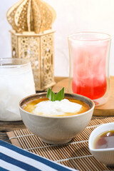 Bubur Sumsum served on wooden table, Javanese dessert porridge of rice flour, coconut milk with brown sugar syrup. A popular iftar food for breaking the fast Ramadan
