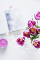 A bouquet of tulips and a magenta candle with lights and a notepad.