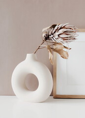 Modern ceramic vase with dry flower protea on beige  background .Neutral colors. Photo frame,...