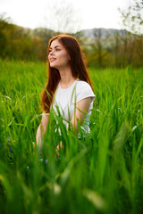cute, happy woman in white t-shirt midit in green grass