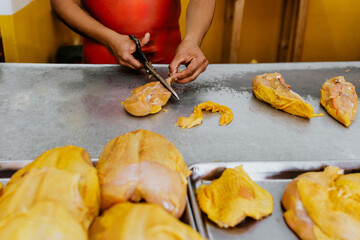 latin man hands of Poultry vendor with raw chickens being sliced by the Pollero at Chicken shop or Polleria in Mexican market in Mexico Latin America