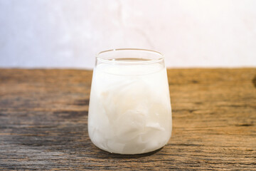 a glass of coconut water on a wooden table. Coconut water can prevent vomiting and treat dehydration. Not only that, coconut water also contains potassium, sodium, electrolytes, calcium and vitamin C