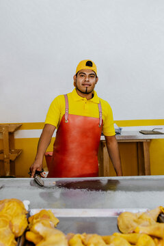Latin man working as Poultry vendor of raw chickens being sliced by the Pollero at Chicken shop or Polleria in Mexican market in Mexico, Hispanic people