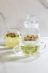 Organic Chrysanthemum flower tea in a cup and teapot on Marble background, Healthy Herbal drink