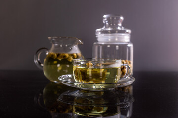 Organic Chrysanthemum flower tea in a cup and teapot on black background, Healthy Herbal drink