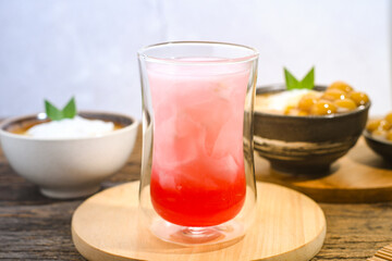 a glass of coconut water with red syrup on a wooden table. Coconut water can prevent vomiting and treat dehydration. Ramadan iftar meal