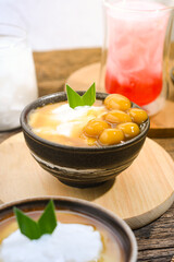 Bubur Sumsum Biji Salak or Candil Ubi served on wooden table, Indonesian traditional dessert porridge of rice flour, coconut milk with brown sugar syrup. Ramadhan iftar food