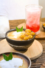 Bubur Sumsum Biji Salak or Candil Ubi served on wooden table, Indonesian traditional dessert porridge of rice flour, coconut milk with brown sugar syrup. Ramadhan iftar food