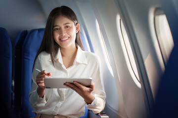 Fototapeta premium Beautiful Asian businesswoman working with digital tablet in aeroplane. working, travel, business concept