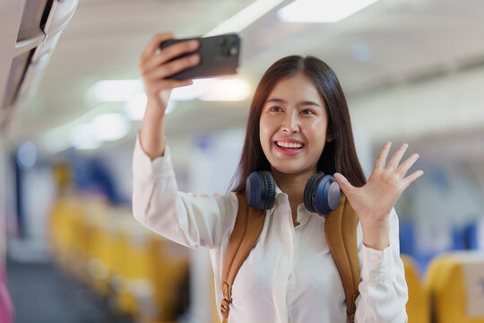Beautiful Asian traveler woman selfie a photo by mobile phone during flight in aeroplane. working, travel, business concept