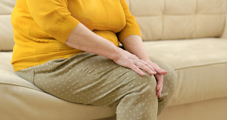 Senior fat woman holding the knee with pain.