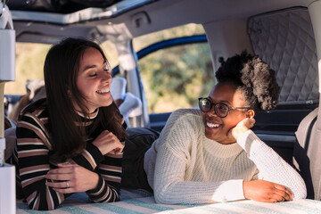 two young women enjoying van life relaxation, concept of weekend getaway with friend and road trip...