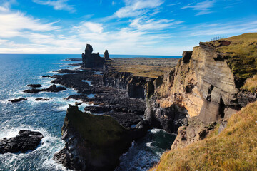 Dramatic cliffs along the Icelandic coastline, with jagged rock formations rising from the ocean...