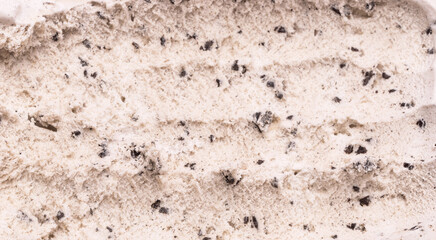 Close-up of Cookies and Cream flavored ice cream being scooped into grooves by a steel spoon.