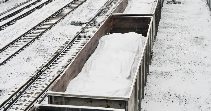 Cargo transportation. A freight train with bags of lime in open wagons passes along the railway track. Hand held.