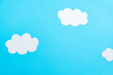 White paper clouds and sky concept on a blue paper, flat lay, top view