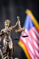 Scales of Justice, Justitia, Lady Justice in front of the American flag in the background.