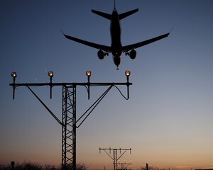 silueta de un  avión aterrizando en el aeropuerto sobre las luces de aproximación a la pista