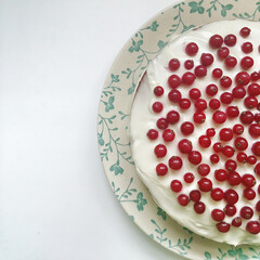 chocolate cake with cream decorated with red currant berries on white background top view