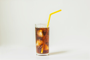 Cola in glass with straw and ice cubes isolated on white