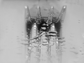 Macro de un tenedor con gotas de agua reflejado en un espejo en blanco y negro