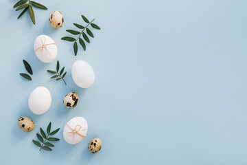 Composition with Easter eggs and spring green leaves on blue background. Minimal easter concept.